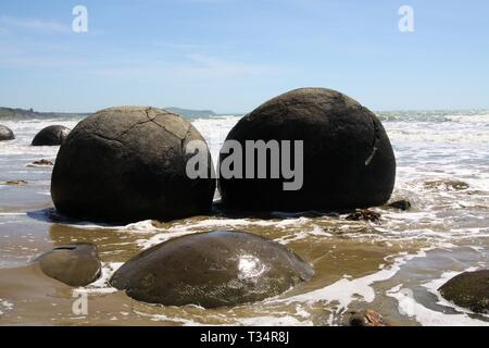 Close up de Moeraki Boulders sphérique de pélites sur la plage baignée par les vagues déferlantes de la mer, Koekohe plage, plage de galets, Nouvelle-Zélande Banque D'Images