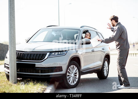 L'assistance routière d'aider les jeunes travailleurs Femme à sortir de la route après l'accident sur l'autoroute Banque D'Images