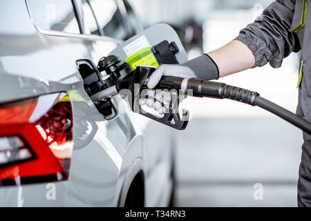 Travailleur station refueling car avec de l'essence, close-up view l'accent sur le pistolet de remplissage Banque D'Images