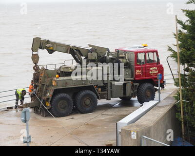 Sheerness, Kent, UK. 06 avril 2019. La récupération d'une excavatrice gridlocked endommagé par l'eau des routes sur les Île de Sheppey dans le Kent cet après-midi qu'il a fallu plusieurs heures pour récupérer sur Marine Parade, Sheerness par le club de voile. Un camion de récupération et une autre grande pelle hydraulique ont été utilisées pour essayer de manœuvrer le pelle cassée sur une remorque. Travailler à charger sur la remorque a débuté à 13h30, mais s'est jusqu'à 17h. La première excavatrice ont échoué à travailler sur les défenses de la mer pour l'Agence de l'environnement, et a été submergé par la mer après le tuyau du moteur a éclaté le 14 mars. Credit : James Bell/Alamy Live News Banque D'Images