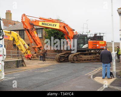Sheerness, Kent, UK. 06 avril 2019. La récupération d'une excavatrice gridlocked endommagé par l'eau des routes sur les Île de Sheppey dans le Kent cet après-midi qu'il a fallu plusieurs heures pour récupérer sur Marine Parade, Sheerness par le club de voile. Un camion de récupération et une autre grande pelle hydraulique ont été utilisées pour essayer de manœuvrer le pelle cassée sur une remorque. Travailler à charger sur la remorque a débuté à 13h30, mais s'est jusqu'à 17h. La première excavatrice ont échoué à travailler sur les défenses de la mer pour l'Agence de l'environnement, et a été submergé par la mer après le tuyau du moteur a éclaté le 14 mars. Credit : James Bell/Alamy Live News Banque D'Images