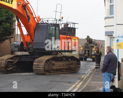 Sheerness, Kent, UK. 06 avril 2019. La récupération d'une excavatrice gridlocked endommagé par l'eau des routes sur les Île de Sheppey dans le Kent cet après-midi qu'il a fallu plusieurs heures pour récupérer sur Marine Parade, Sheerness par le club de voile. Un camion de récupération et une autre grande pelle hydraulique ont été utilisées pour essayer de manœuvrer le pelle cassée sur une remorque. Travailler à charger sur la remorque a débuté à 13h30, mais s'est jusqu'à 17h. La première excavatrice ont échoué à travailler sur les défenses de la mer pour l'Agence de l'environnement, et a été submergé par la mer après le tuyau du moteur a éclaté le 14 mars. Credit : James Bell/Alamy Live News Banque D'Images