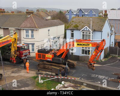 Sheerness, Kent, UK. 06 avril 2019. La récupération d'une excavatrice gridlocked endommagé par l'eau des routes sur les Île de Sheppey dans le Kent cet après-midi qu'il a fallu plusieurs heures pour récupérer sur Marine Parade, Sheerness par le club de voile. Un camion de récupération et une autre grande pelle hydraulique ont été utilisées pour essayer de manœuvrer le pelle cassée sur une remorque. Travailler à charger sur la remorque a débuté à 13h30, mais s'est jusqu'à 17h. La première excavatrice ont échoué à travailler sur les défenses de la mer pour l'Agence de l'environnement, et a été submergé par la mer après le tuyau du moteur a éclaté le 14 mars. Credit : James Bell/Alamy Live News Banque D'Images