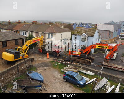 Sheerness, Kent, UK. 06 avril 2019. La récupération d'une excavatrice gridlocked endommagé par l'eau des routes sur les Île de Sheppey dans le Kent cet après-midi qu'il a fallu plusieurs heures pour récupérer sur Marine Parade, Sheerness par le club de voile. Un camion de récupération et une autre grande pelle hydraulique ont été utilisées pour essayer de manœuvrer le pelle cassée sur une remorque. Travailler à charger sur la remorque a débuté à 13h30, mais s'est jusqu'à 17h. La première excavatrice ont échoué à travailler sur les défenses de la mer pour l'Agence de l'environnement, et a été submergé par la mer après le tuyau du moteur a éclaté le 14 mars. Credit : James Bell/Alamy Live News Banque D'Images