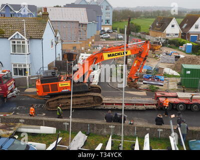 Sheerness, Kent, UK. 06 avril 2019. La récupération d'une excavatrice gridlocked endommagé par l'eau des routes sur les Île de Sheppey dans le Kent cet après-midi qu'il a fallu plusieurs heures pour récupérer sur Marine Parade, Sheerness par le club de voile. Un camion de récupération et une autre grande pelle hydraulique ont été utilisées pour essayer de manœuvrer le pelle cassée sur une remorque. Travailler à charger sur la remorque a débuté à 13h30, mais s'est jusqu'à 17h. La première excavatrice ont échoué à travailler sur les défenses de la mer pour l'Agence de l'environnement, et a été submergé par la mer après le tuyau du moteur a éclaté le 14 mars. Credit : James Bell/Alamy Live News Banque D'Images