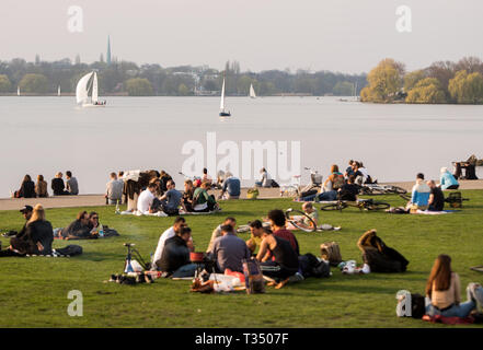 Hambourg, Allemagne. 06 avr, 2019. De nombreuses personnes s'asseoir au soleil sur un pré sur l'Alster. Crédit : Daniel Bockwoldt/dpa/Alamy Live News Banque D'Images