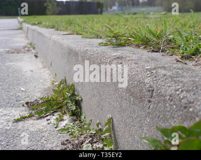 Low angle view vue de freiner ou d'une bordure en pierre à pierre une place de parking. À la frontière des terres de l'herbe. Banque D'Images