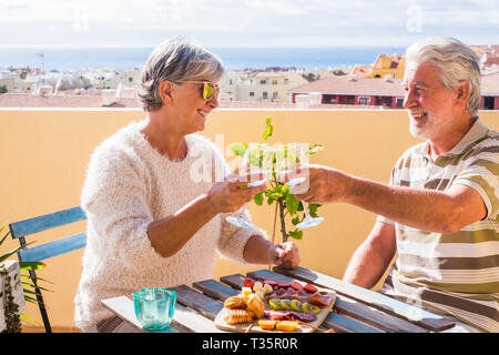 Beau couple de retraités des profils rester ensemble sur le roofto pterrace boire et manger certains aliments et boissons. sourire heureux les gens en plein air grand lifesty Banque D'Images