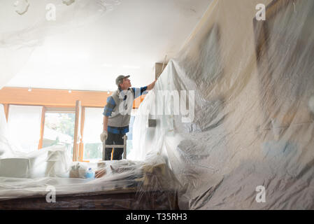 Peintre en peinture de l'intérieur d'une chambre meublé Banque D'Images