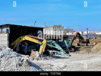 Old rusty construction abandonnée pelles avec un godet au sol dans un hangar sur un site de construction Banque D'Images
