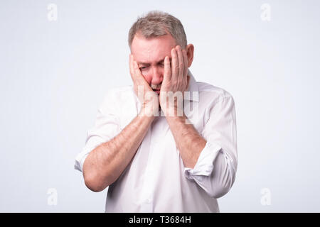 Les gars en chemise blanche à la satisfait et fatigué. Il a une mauvaise journée, pense à ses problèmes au travail. Banque D'Images