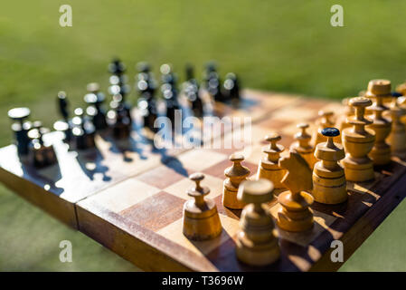 Échecs échiquier de vieux et de l'ombre, isolé sur un green, arrière-plan flou. Banque D'Images