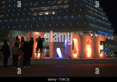 Kobe, Hyogo, Japon - 16 novembre 2018 : Photo de quelques personnes debout en face de l'éclairage d'être 'KOBE' monument avec le Kobe Meriken Park Ho Banque D'Images