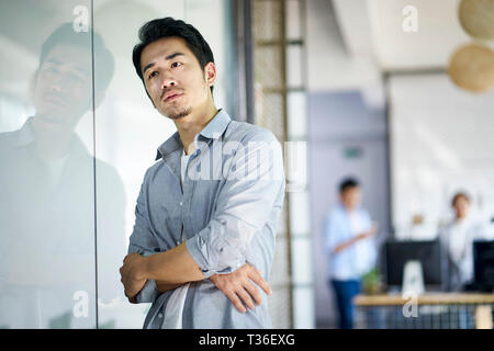 Jeune entrepreneur asiatique ou le concepteur pense en bureau de l'entreprise. Banque D'Images