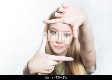 Belle jeune femme fait un cadre avec ses doigts, à la recherche d'un bon groupe Banque D'Images