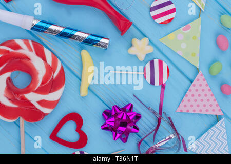 Mise à plat avec les éléments de la composition du parti. Carnaval haut en couleurs ou anniversaire de fond avec des streamers, sucettes, arcs et autres accessoires sur bleu wo Banque D'Images