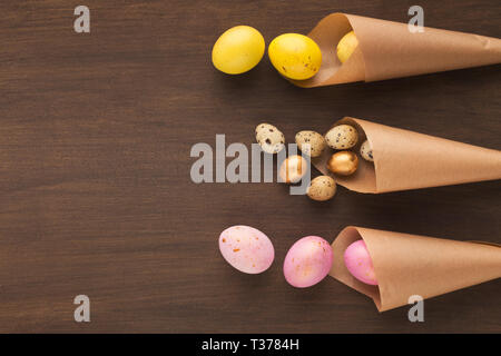 Composition de Pâques avec des oeufs colorés dans du papier craft cornets, vue de dessus, copy space Banque D'Images