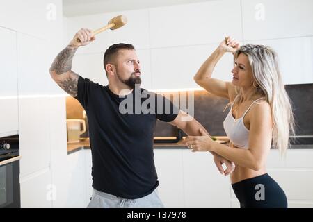 Mari et femme dans l'affrontement avec cuisine rouleau à pâtisserie et la viande maillet. Relation entre l'homme et de la femme. Banque D'Images