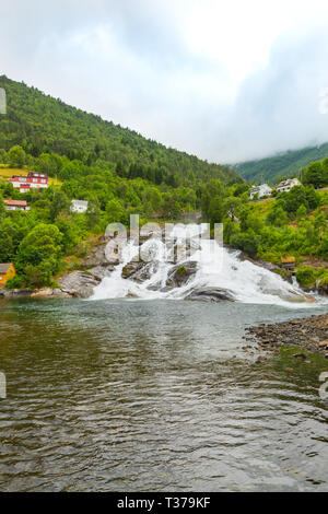 Maisons sur le flanc par le lac, près de la cascade. La montagne se jette dans le lac du haut de la montagne. Banque D'Images