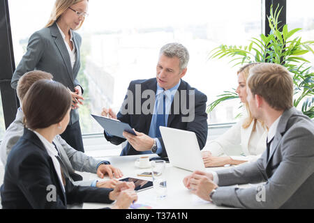 Groupe mixte de travailleurs en col blanc réunion d'affaires à l'homme d'affaires, discuter des documents du contrat de lecture à table office Banque D'Images
