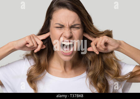 Portrait de femme hurlant fermer les oreilles avec les doigts Banque D'Images
