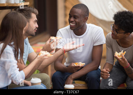 Heureux multiraciale friends laughing at blague eating pizza in cafe Banque D'Images