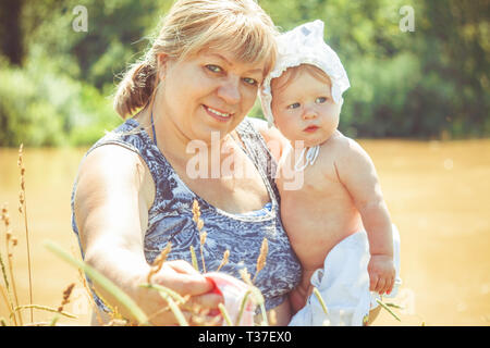 Grand-mère est titulaire d'une petite fille nouveau-né dans ses bras. Banque D'Images