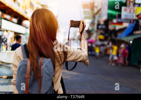 Young Woman Woman holding a camera et prendre des photos à Bangkok, Thaïlande lors d'un voyage en Asie du sud-est Banque D'Images