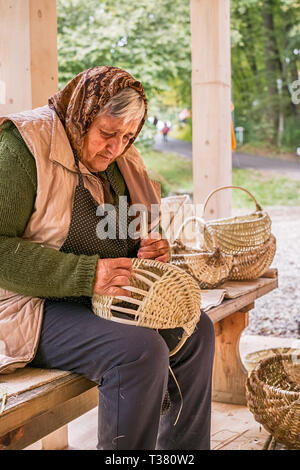 La ville de Sibiu, Roumanie - 30 septembre 2018. Une vieille femme roumaine tisse des paniers en osier Banque D'Images