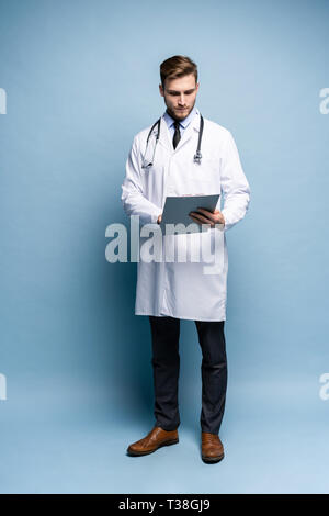 Médecin Homme debout avec dossier, Doc est le port de l'uniforme blanc et une cravate, se dresse sur un fond bleu clair. Banque D'Images