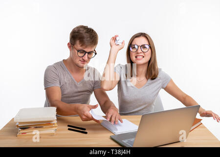 Espiègle, naughty étudiants avec grands verres jeter papier froissé assis à la table. Banque D'Images