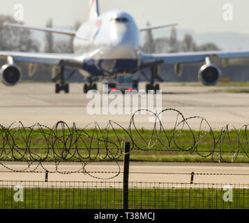 Londres, ANGLETERRE - Mars 2019 : Sécurité barrière de barbelés autour du périmètre de l'aéroport de London Heathrow Airport. Un avion est dans l'arrière-plan Banque D'Images