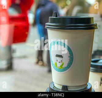 Le café dans une tasse de papier avec une photo amusante en face de la vitrine Banque D'Images