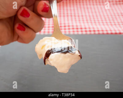 Une femme avec des ongles peints en rouge avec une cuillère dans sa main avec la crème, sauce au chocolat et de couleur chocolat Banque D'Images