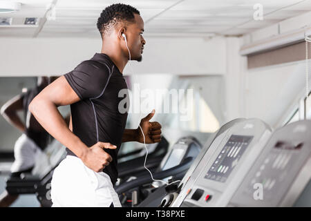 Jeune homme noir africain-américain de faire l'exercice dans la salle de sport cardio Banque D'Images