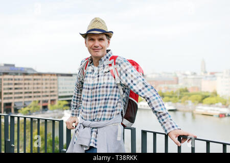 Homme mûr en chapeau de paille avec sac à dos, debout sur une terrasse à Helsinki, Finlande Banque D'Images