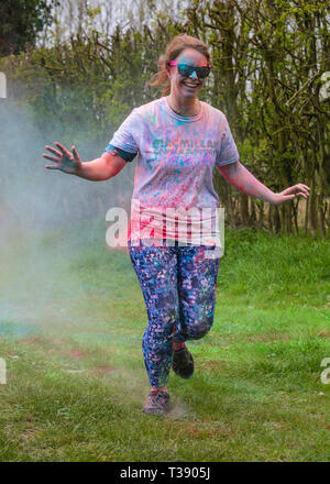 Coureuse de rire et de se couvrir de peinture sur Macmillan Cancer 5K fun run de couleur. Banque D'Images
