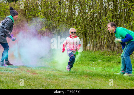 Petit garçon exécutant dur et se couvrir de peinture sur Macmillan Cancer 5K fun run de couleur. Banque D'Images