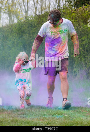 Père et sa petite fille couverte de peinture sur Macmillan Cancer 5K fun run de couleur. Banque D'Images