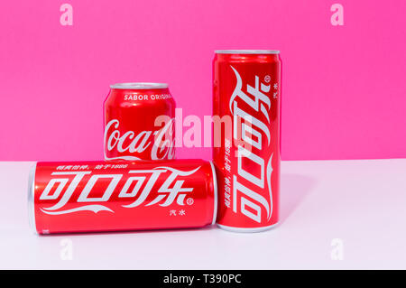 Peniscola , Paris, France - 07 avril 2019 : trois canettes de Coke, deux écrits en chinois, des boissons isolé sur un fond de couleur rose. La non-alcool Banque D'Images