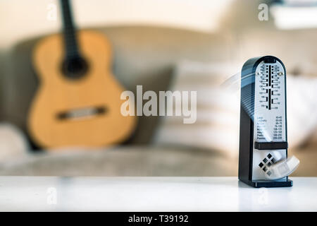 Métronome mécanique en mouvement, sur une guitare acoustique classique en arrière-plan. Banque D'Images