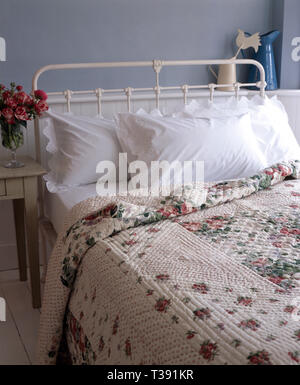 Courtepointe à motifs de roses et blancs vintage oreillers sur un lit en fer forgé Banque D'Images