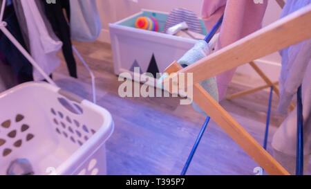 Soft, defocused blanchisserie scène dans une salle de séjour, avec des vêtements sur des séchoirs, panier de blanchisserie et coffre à jouets. Banque D'Images