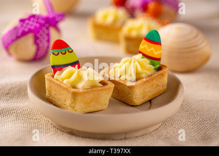 Mini tartelettes à la crème de fromage décoré avec des oeufs de Pâques au chocolat Banque D'Images