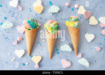 Ice cream cones dans couleurs arc-en-ciel avec des bonbons colorés Banque D'Images