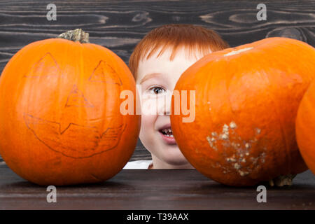 Un petit garçon derrière une citrouille tout en célébrant ou en préparation d'une célébration de l'Halloween Banque D'Images