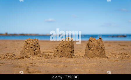 Châteaux de sable sur la plage de sables bitumineux, Runswick North Yorkshire, Angleterre Royaume-uni - avec la mer du Nord à l'arrière-plan Banque D'Images