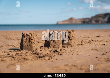 Châteaux de sable sur la plage de sables bitumineux, Runswick North Yorkshire, Angleterre Royaume-uni - Kettleness avec en arrière-plan Banque D'Images