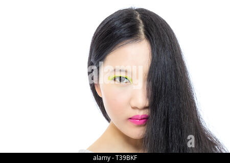 Teenage Asian high school girl maquillage rose et vert avec cheveux pendants devant la moitié de visage Banque D'Images