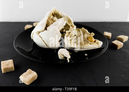La meringue avec les écrous sur une plaque noire. Mode Macro. Le sucre de canne. Candy. Banque D'Images